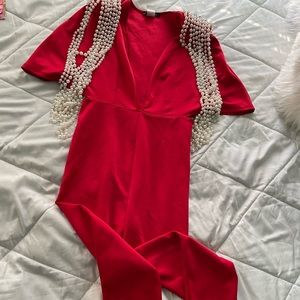 Vibrant Red Jumpersuit with structured pearl draped along shoulder pads.